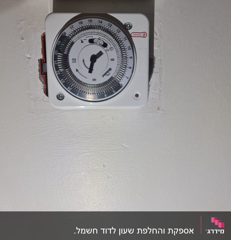 טיימר חשמלי עם חוגה על קיר לבן